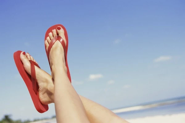 Feet in flip flops on beach