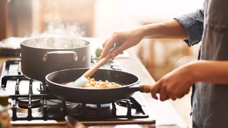 Γυναίκα που μαγειρεύει και ετοιμάζει φαγητό στο τηγάνι