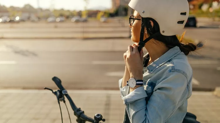 Γυναίκα που φοράει το κράνος της για να κάνει ποδήλατο