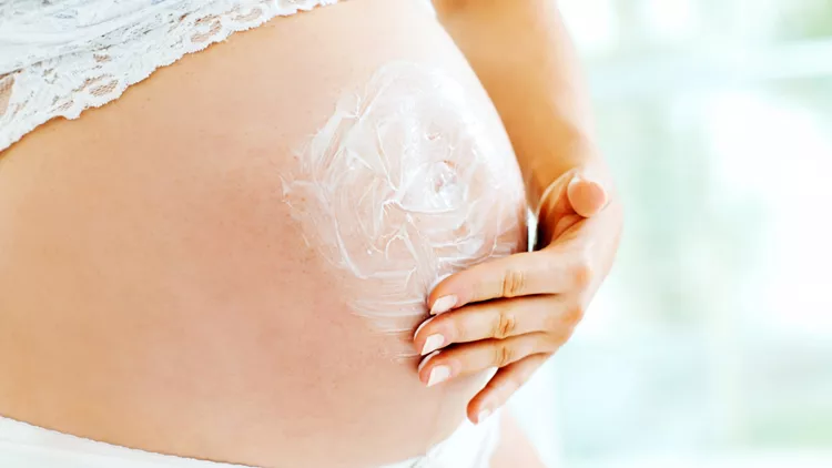 εγκυος γυναίκα απλώνει λοσιόν για τις ραγάδες της εγκυμοσύνης