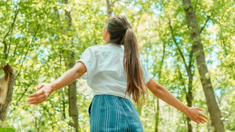 Γυναίκα που αναπνέει καθαρό αέρα σε πάρκο στη φύση