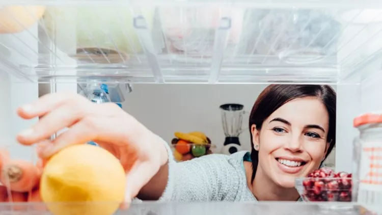 woman-taking-a-lemon-out-of-the-fridge-picture-id669677488