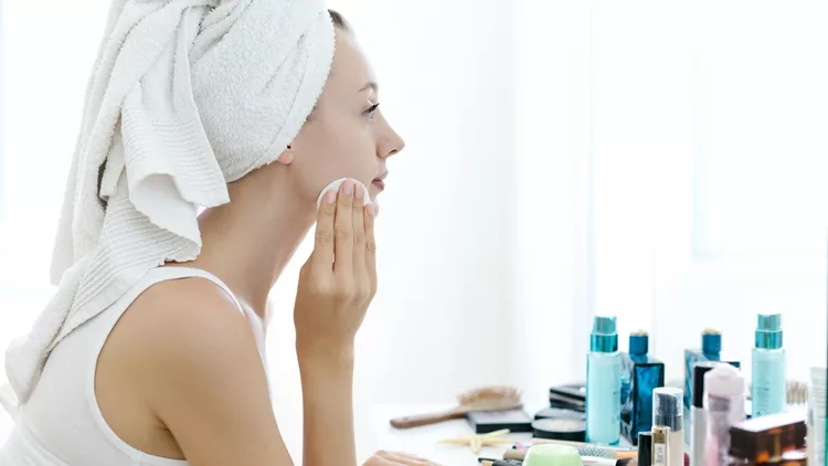 Young woman removing makeup from her face