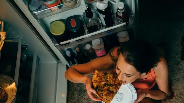 woman-eating-in-front-of-the-refrigerator-in-the-kitchen-late-night-picture-id966461220