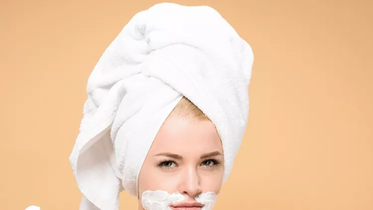 young-woman-with-towel-on-head-and-shaving-cream-on-face-holding-and-picture-id1097826860 (1)