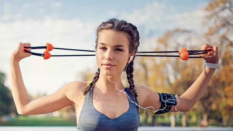 young-girl-is-doing-resistance-band-exercises-in-the-park-picture-id907888884