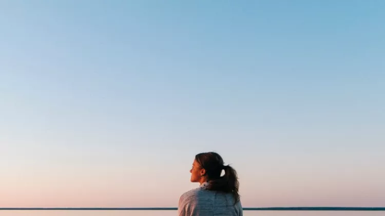 young-woman-sitting-on-edge-looks-out-at-view-picture-id1065043970