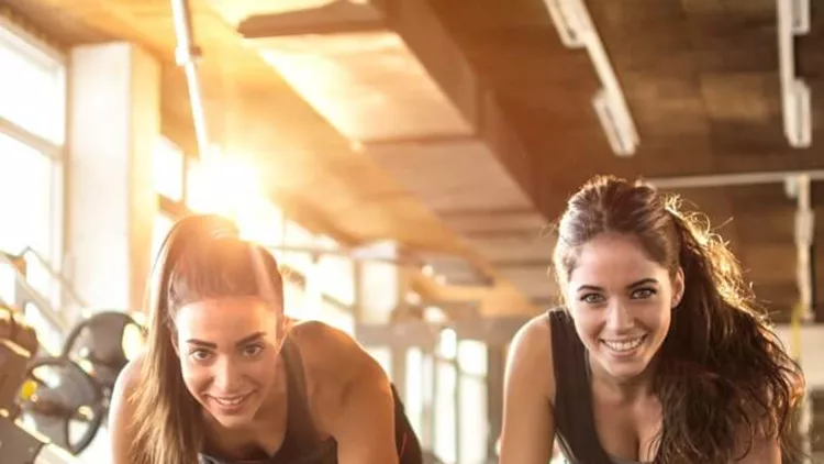 two-sporty-girls-doing-push-ups-in-gym-picture-id636947568
