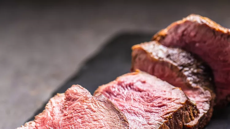 juicy-beef-steak-with-spices-and-herbs-on-wooden-cutting-board-picture-id1035020292