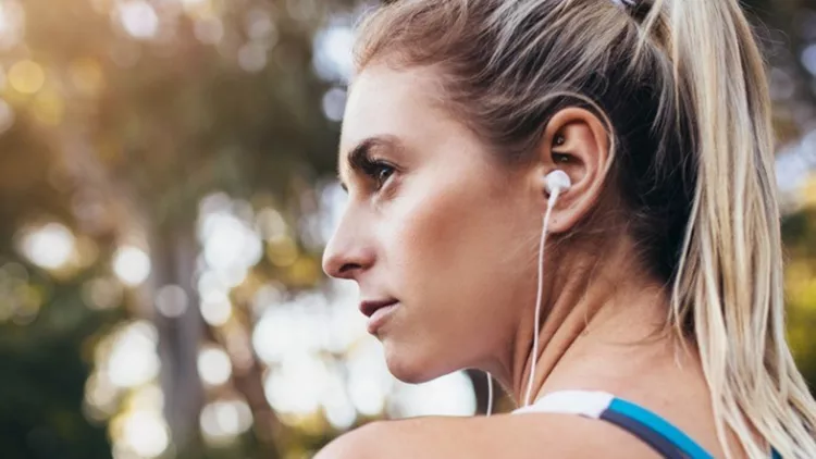 woman-runner-wearing-earphones-during-workout-picture-id868611064