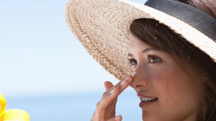 woman-with-straw-hat-applying-sunblock-to-face-outdoors-picture-id178545672