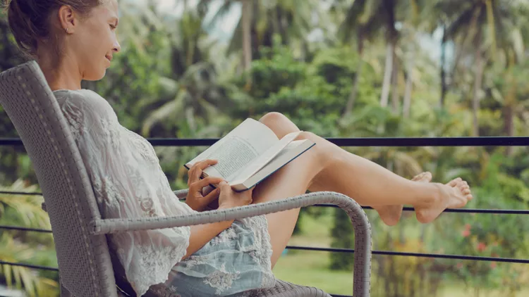 Young woman reading a book while relaxing on tropical island
