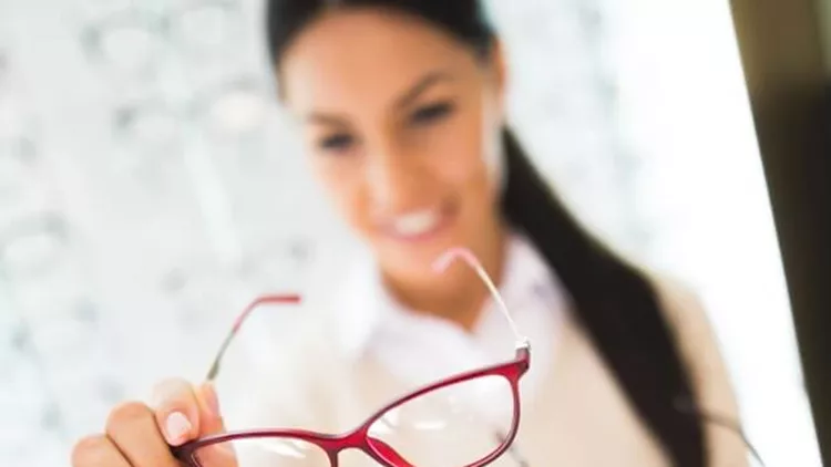 woman-selecting-eyeglasses-in-optical-store-picture-id625596630