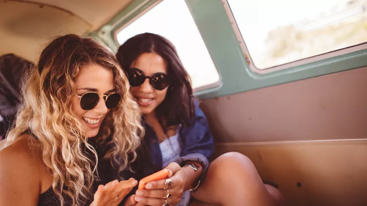 Two Hipster Girls Sitting Together in van Looking at Phone
