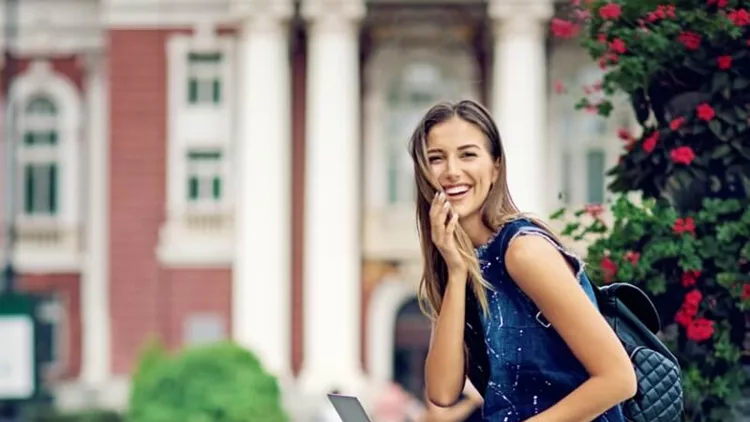 young-girl-is-sitting-on-the-city-fountain-and-using-her-laptop-picture-id823759776