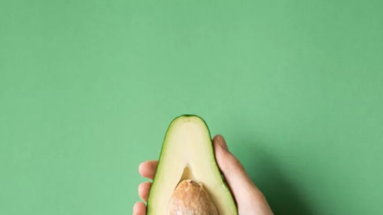 avocado-in-a-hand-of-woman-colored-background-healthy-food-concept-picture-id841456898