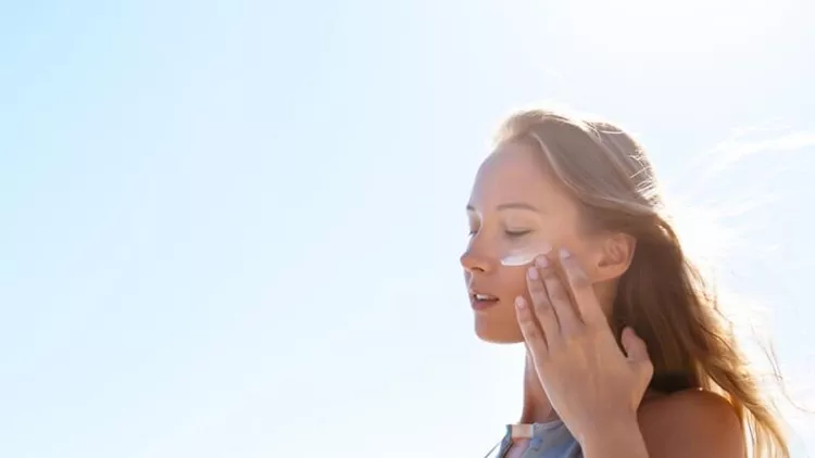 beautiful-model-applying-sunscreen-for-her-face-on-the-beach-picture-id955828498