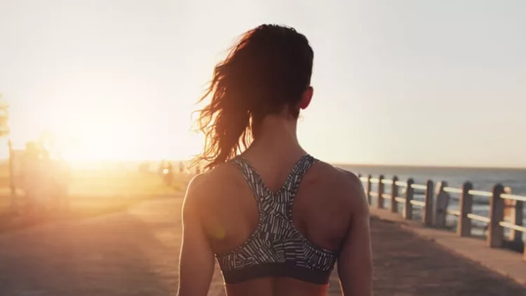 fitness-woman-walking-on-a-seaside-promenade-at-sunset-picture-id539371278