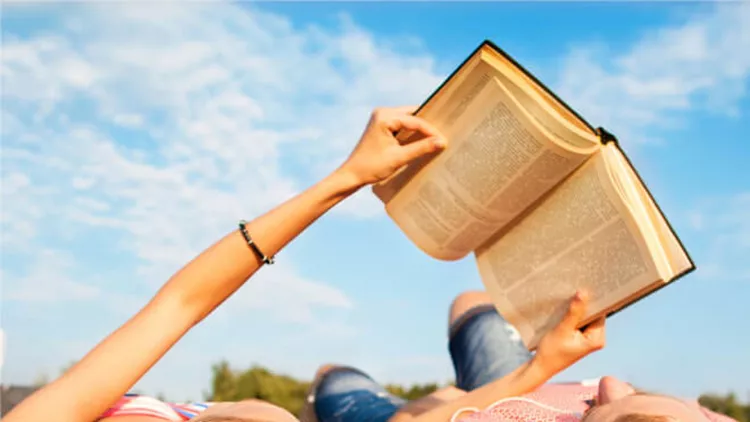 girl-and-guy-lying-on-the-grass-reading-a-book-relaxing-in-the-park-picture-id922543750