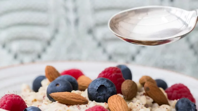 close-up-of-woman-eating-bowl-of-porridge-with-fruit-and-nuts-for-picture-id927961622