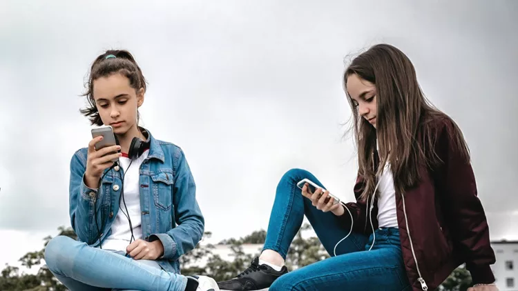 three-teenage-girls-with-smartphones-on-concrete-wall-picture-id818305886