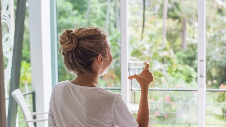 beautiful-young-woman-holding-a-glass-of-water-picture-id917986930