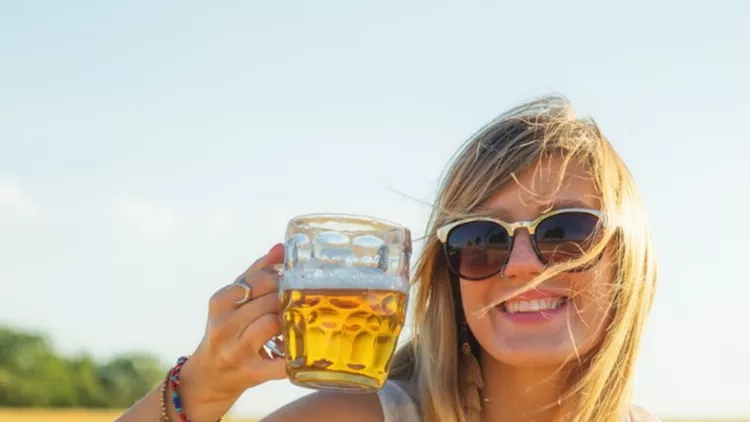 happy-girl-holding-beer-glass-in-a-big-wheatfield-picture-id823734004