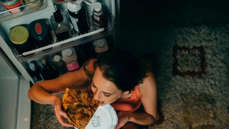 woman-eating-in-front-of-the-refrigerator-in-the-kitchen-late-night-picture-id966461220