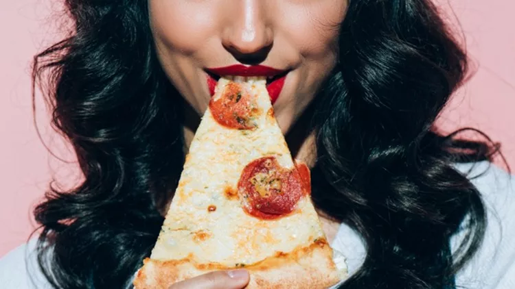 cropped-shot-of-woman-eating-pizza-on-pink-background-picture-id942927444 (1)