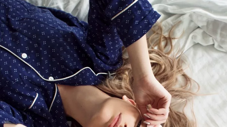 cute-blonde-in-her-bed-in-blue-pajamas-and-sleep-mask-top-view-picture-id855117644