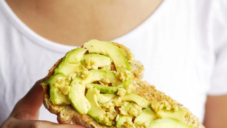 woman-hand-show-eating-avocado-bread-cheese-toast-white-tshirt-picture-id891931888