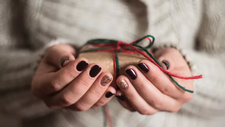 girl holding a gift box. Manicure gel nail