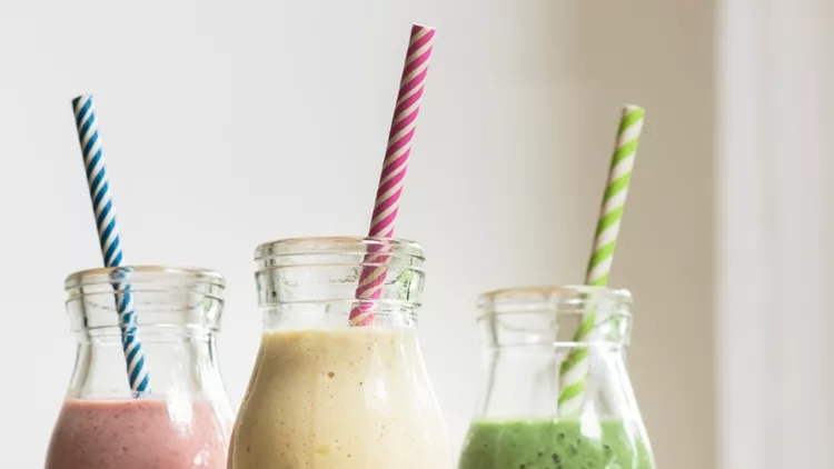 three-fruit-and-vegetable-smoothies-in-glass-bottles-with-straws-picture-id607655626