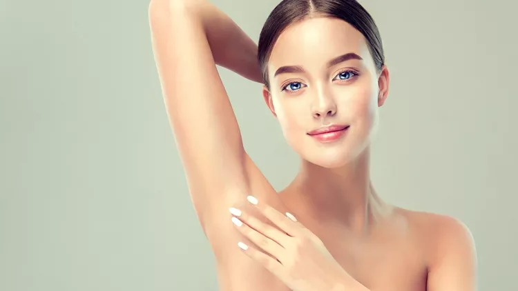 Young, blue-eyed woman is holding her arm up and showing clean underarm. Cosmetology and armpit epilation. Cosmetology.
