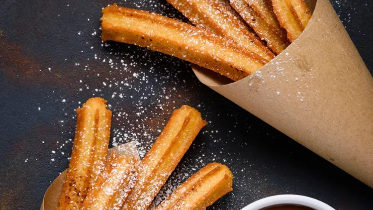 churros-sticks-in-paper-bag-with-sugar-powder-cinnamon-picture-id1135149297