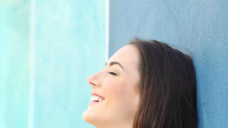 happy-woman-resting-leaning-on-a-colorful-wall-picture-id1142820508