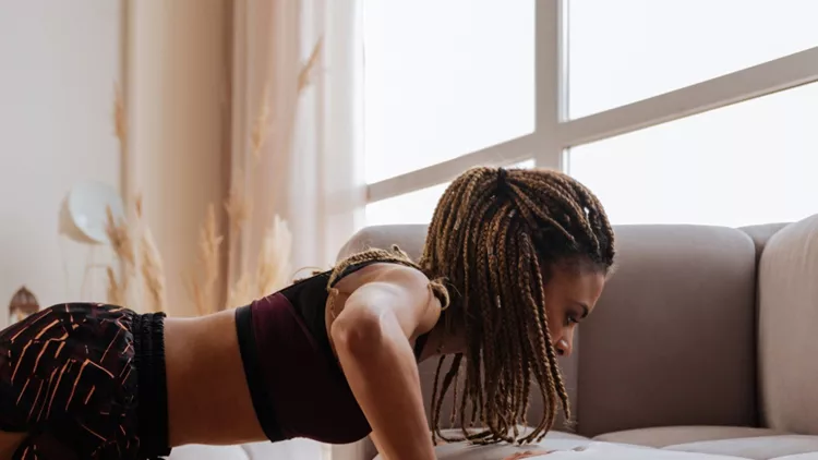 woman-wearing-shorts-and-top-doing-pushups-near-sofa-picture-id1140193320