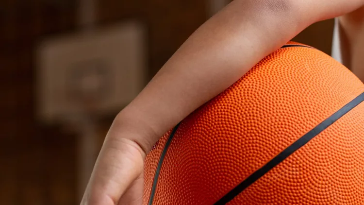 schoolboy-with-basketball-standing-in-basketball-court-picture-id1133790384