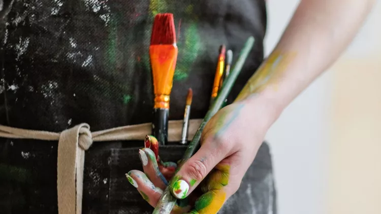 woman-artists-hand-with-a-brush-and-red-paint-black-apron-white-picture-id1098009480