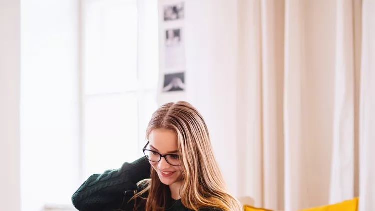 young-female-student-sitting-on-sofa-using-laptop-when-studying-picture-id1156480842