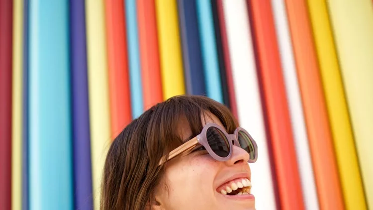 close-up-cheerful-young-woman-laughing-with-sunglasses-against-picture-id1204482432