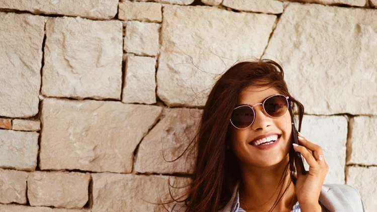 happy-brunette-woman-drinking-coffee-and-talking-on-the-phone-picture-id883115788