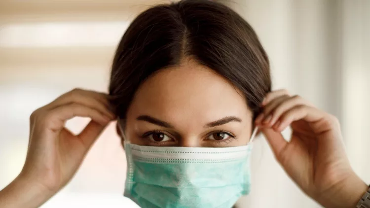 portrait-of-young-woman-putting-on-a-protective-mask-picture-id1217604429