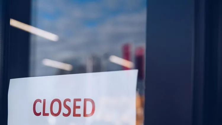 woman-hangs-a-card-with-information-about-the-store-closing-on-a-shop-picture-id1212066260