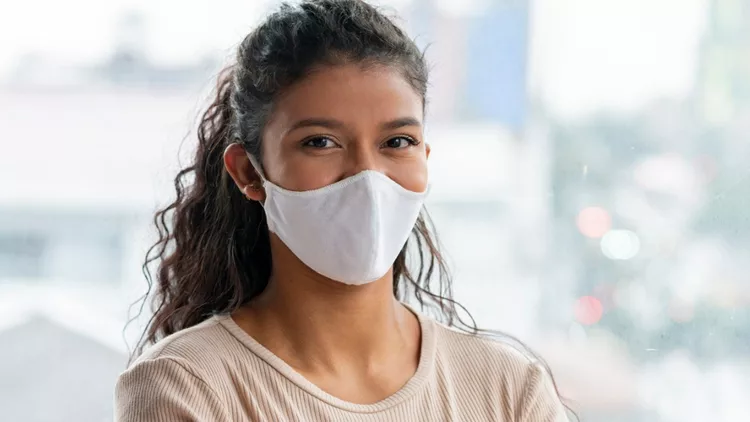 young-latin-woman-smiles-at-the-camera-with-her-mask-on-picture-id1264537571