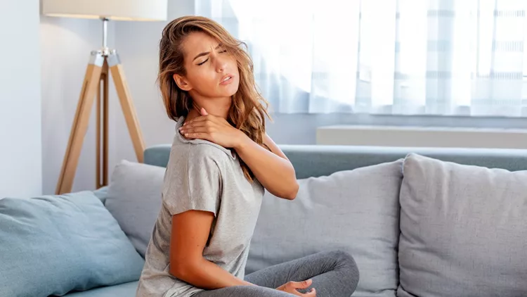 Pain in the shoulder. Upper arm pain, People with body-muscles problem, Healthcare And Medicine concept. Attractive woman sitting on the bed and holding painful shoulder with another hand.