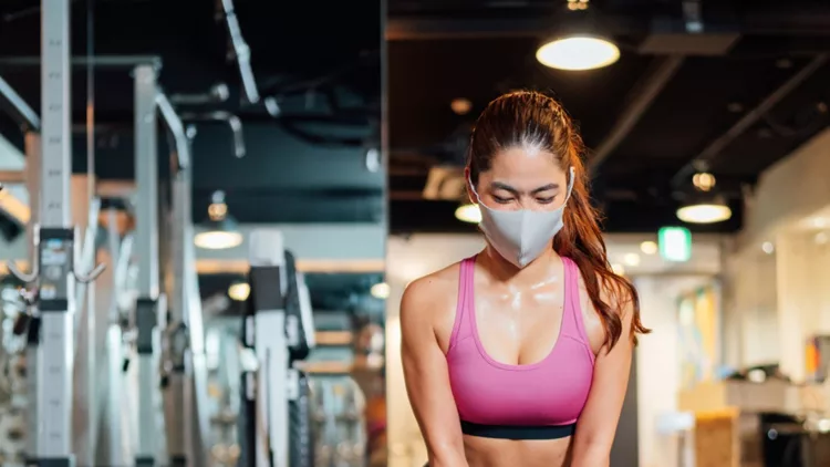 female-athlete-wearing-protective-face-mask-and-lifting-kettlebell-in-picture-id1254069551