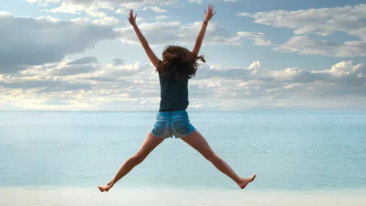 new-year-2021-on-the-sand-happy-girl-with-hands-up-jumping-on-the-picture-id1253432309
