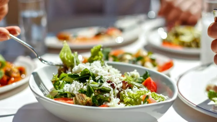 couple-eating-lunch-with-fresh-salad-and-appetizers-picture-id944478708