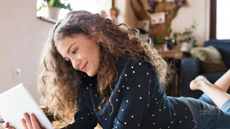 teenage-girl-lying-on-the-floor-holding-tablet-studying-picture-id673405548